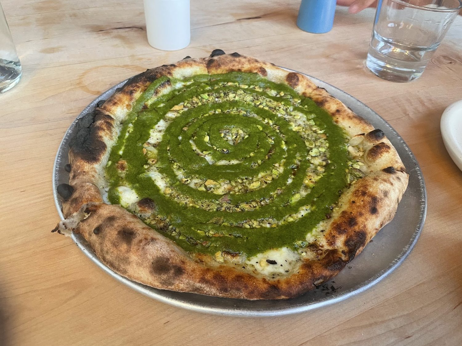 A Verde pizza: a spiral of bright green parsley puree with smoked mozzarella and pistachios